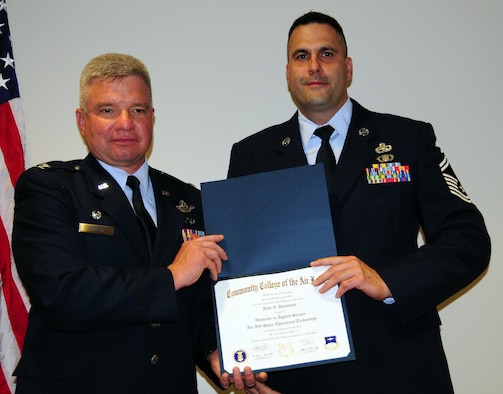 Senior Master Sgt. John DiBattista, fabrications  and elements supervisor, 103rd Maintenance Squadron, receives his diploma from keynote speaker Col. Thomas Powers, commander, 103rd Mission Support Group, during the Fall 2010/Spring 2011 CCAF graduation at Bradley Air National Guard Base, East Granby, Conn. May 14, 2011.
