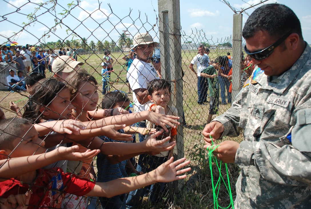 Sergeant Ernie Martinez, 1st Battalion, 228th Aviation Regiment, hands out ribbon to children at an air show June 12, 2011, at Colonel Armando Escalon Espinal Air Base, Honduras.  This annual event drew more than 10,000 people, raised money for a local civilian hospital and gave the opportunity for U.S. military members interact with the local community. Soto Cano AB, Honduras. 