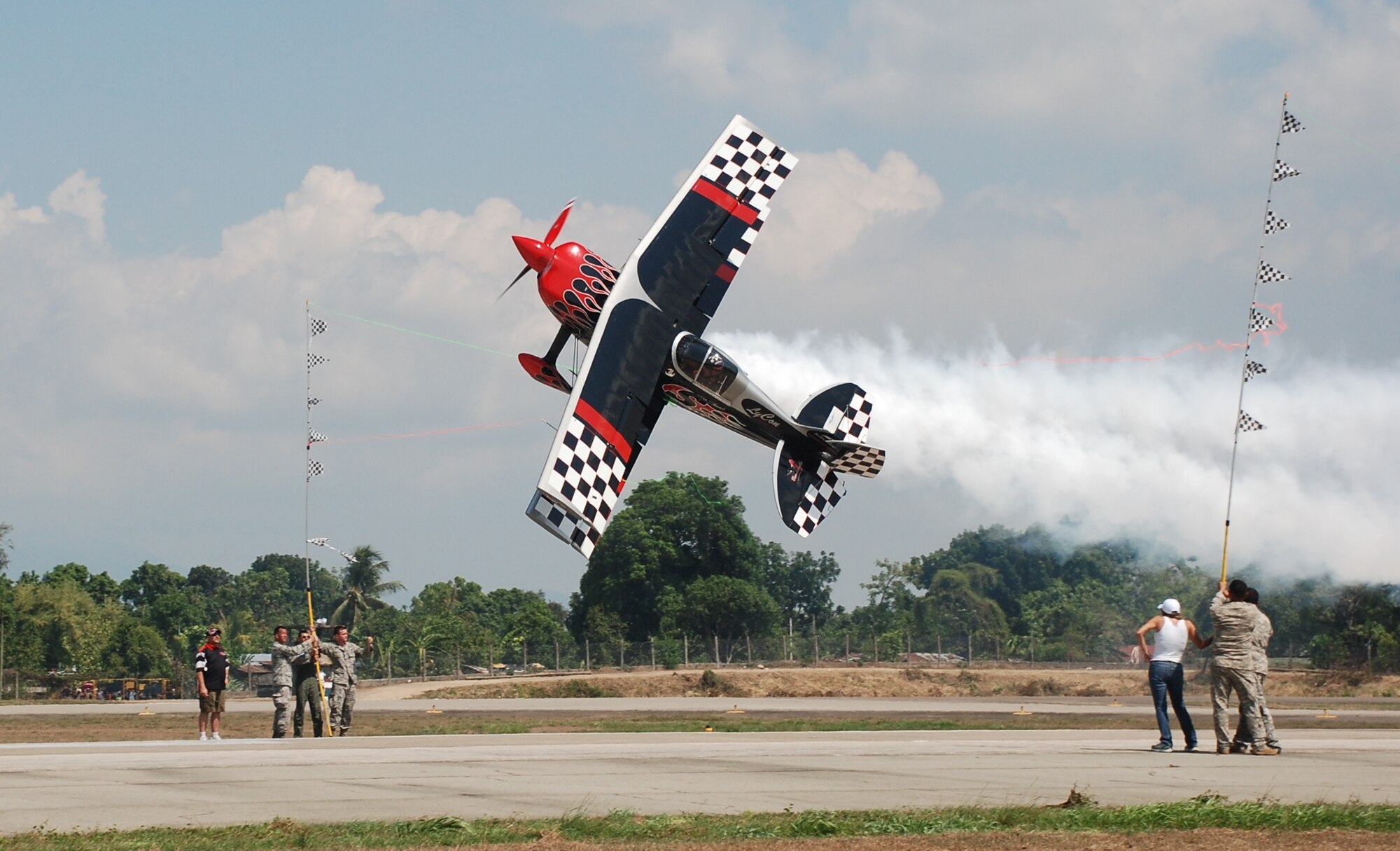 Aerial stunt performer Patty Wagstaff cuts ribbon while flying inverted as Honduran military, U.S. military and civilians assist at an air show June 12, 2011, at Colonel Armando Escalon Espinal Air Base, Honduras.  This annual event drew more than 10,000 spectators, raised money for a local civilian hospital and bolstered friendships between the military and civilian aviation community of the U.S. and Honduras.
