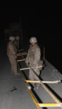 Marines with 7th Engineer Support Battalion, 2nd Marine Logistics Group (Forward) remove the rails from a bridge during an operation in the Gamsir district, Helmand province, Afghanistan, June 16, 2011.  The Marines placed a bridge over the Darvishan Bridge as a temporary fix to allow Afghan contractors to repair it without stopping traffic in the area.  This project will directly benefit the Marines of 1st Battalion, 3rd Marine Regiment, 2nd Marine Division (Fwd.) who are currently operating in the district in support of the International Security Assistance Force as well as the local population.