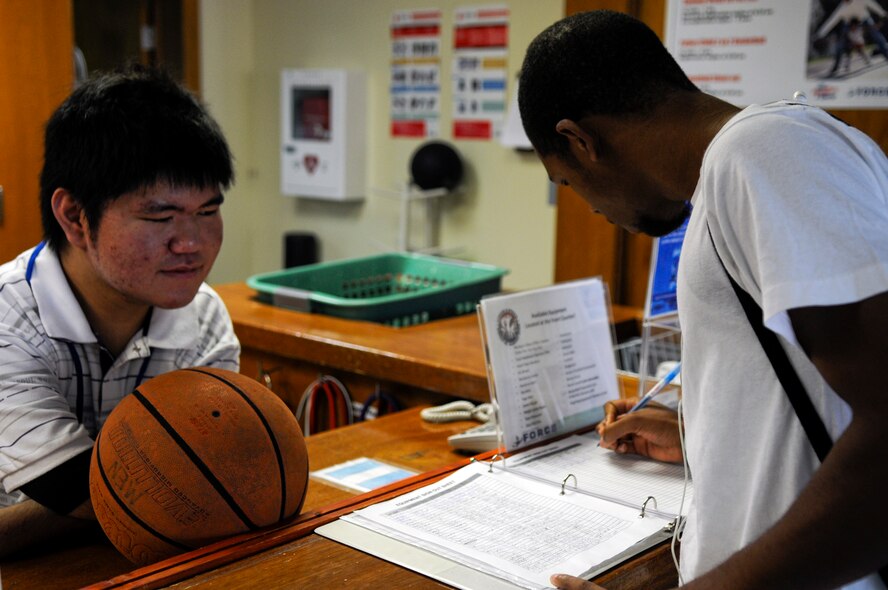 Ryo Oshiro, an Okinawan intern at the Risner Fitness Complex, checks out a basketball to a customer at the Risner on Kadena Air Base, Japan, June 14. Mr. Oshiro, a student from Kagamigaoka Special Education School who has been diagnosed with Marfanoid Hypermobility Syndrome which limits the mobility of his hands, lower back and legs, is working closely with both the Airmen and locally hired staff at the gym to gain further knowledge of American customs and the English language. (U.S. Air Force photo/ Airman 1st Class Maeson L. Elleman)