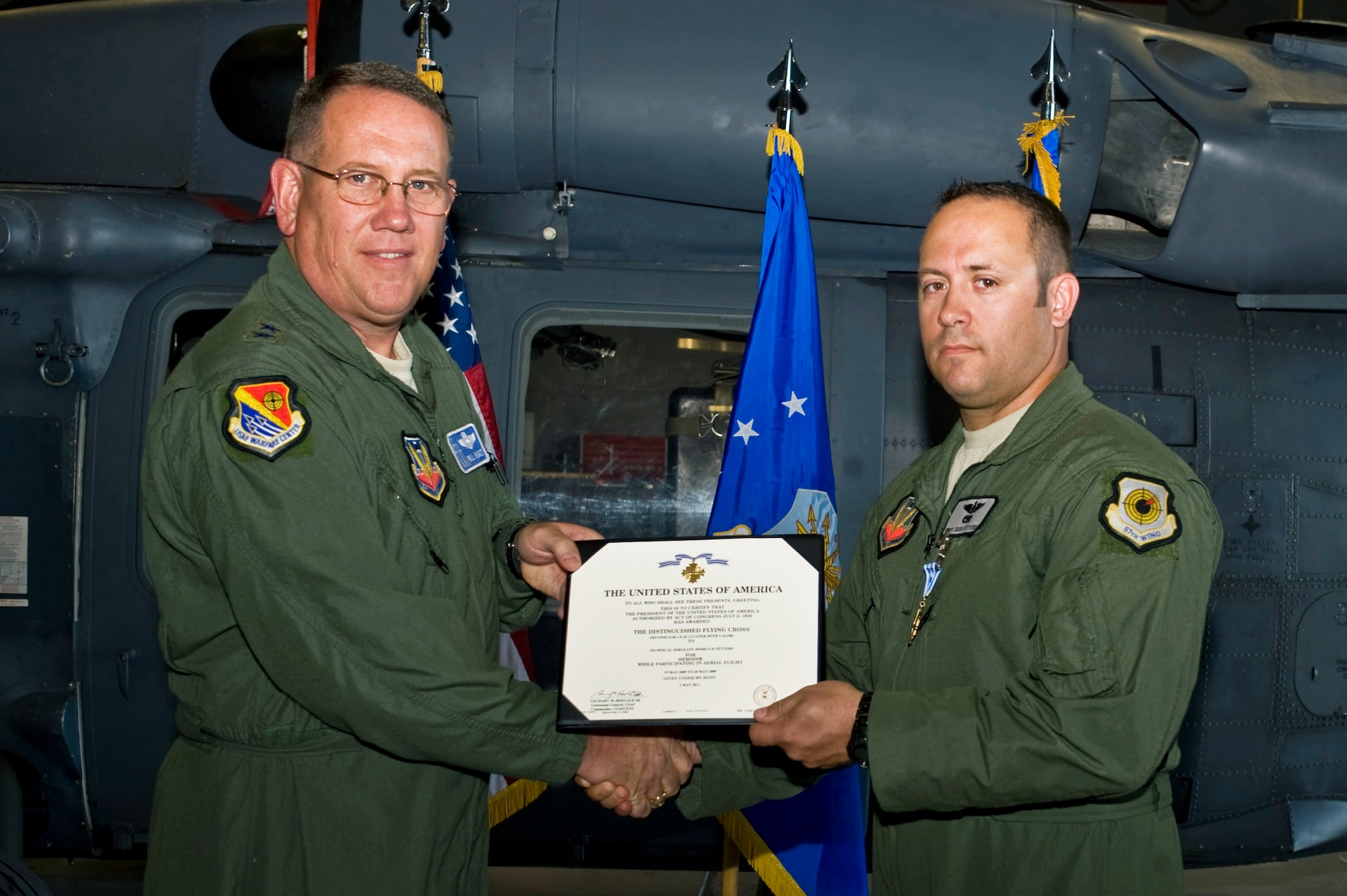 NELLIS AIR FORCE BASE, Nev.-- U.S. Air Force Maj. Gen. James Hyatt presents the Distinguished Flying Cross with valor to Master Sgt. Joshua D. Fetters, 34th Weapons Squadron flight engineer June 15, 2011, at the 763rd Maintenance hangar. Sergeant Fetters received the medal for evacuating injured soldiers from a Taliban stronghold while returning enemy fire May 19, 2009, in Afghanistan. (U.S. Air Force photo by Airman 1st Class Matthew Lancaster)