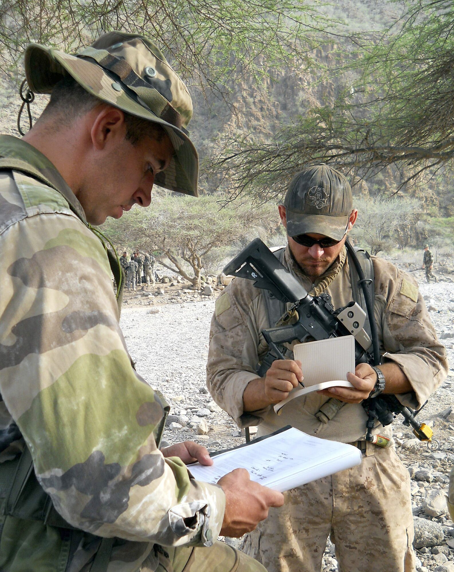A member of the 5th French Marine Regiment translates a page of desert combat training instructions for U.S. Navy Petty Officer 3rd Class Ryan Donofrio (right) during a course which began May 31, 2011, in the Bour Ougoul training area in Djibouti. The 10-day course provided nearly 120 French and 40 U.S. service members with a basic knowledge of field tactics and survival techniques to use in a desert environment. Petty Officer Donofrio is an explosive ordnance disposal technician with Combined Joint Task Force - Horn of Africa. (U.S. Air Force photo/Staff Sgt. R.J. Biermann)