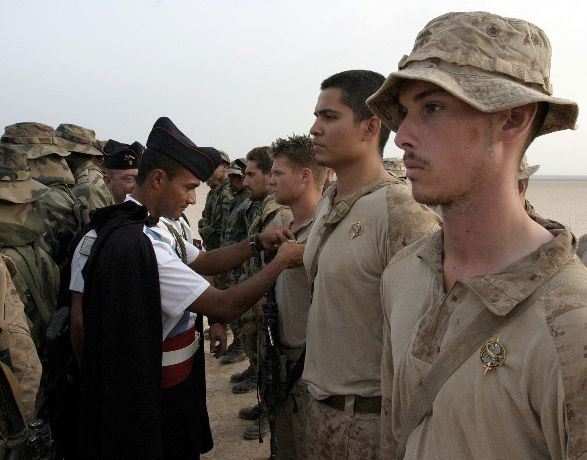 Service members from Camp Lemonnier, Djibouti, are awarded a numbered pin for completing the 5th French Marine Regiment Desert Combat Training course in Djibouti on June 9, 2011. The 10-day course provided nearly 120 French and 40 U.S. troops with a basic knowledge of field tactics and survival techniques to use in a desert environment. (U.S. Marine Corps photo/Lance Corporal Massimo Selim)