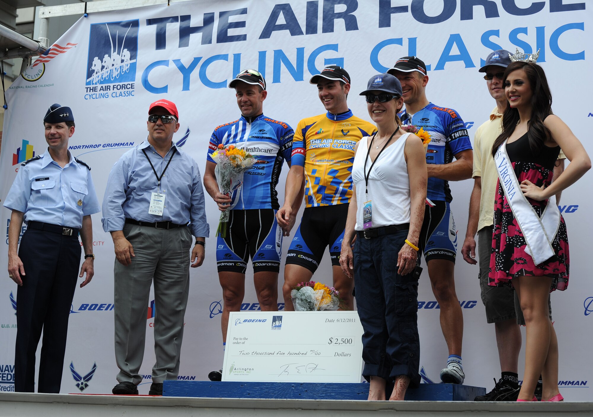 Winners of the Men’s Pro/Am race, Jake Keough-first place, Hilton Clark-second, and Robert Forster-third, are joined on stage by several dignitaries including Lt. Gen. Darrell D. Jones, Air Force Manpower and Personnel director, Headquarters U.S. Air Force, Pentagon, and Miss Virginia, Caitlin Uze, for the presentation of awards for the Men’s Invitational Pro/Am race, June 12, 2011, Crystal City, Va. The Men’s Pro/Am race was one of several races during the annual two-day Air Force Cycling Classic. (U.S. Air Force photo by Master Sgt. Tracy L. DeMarco) (Released)