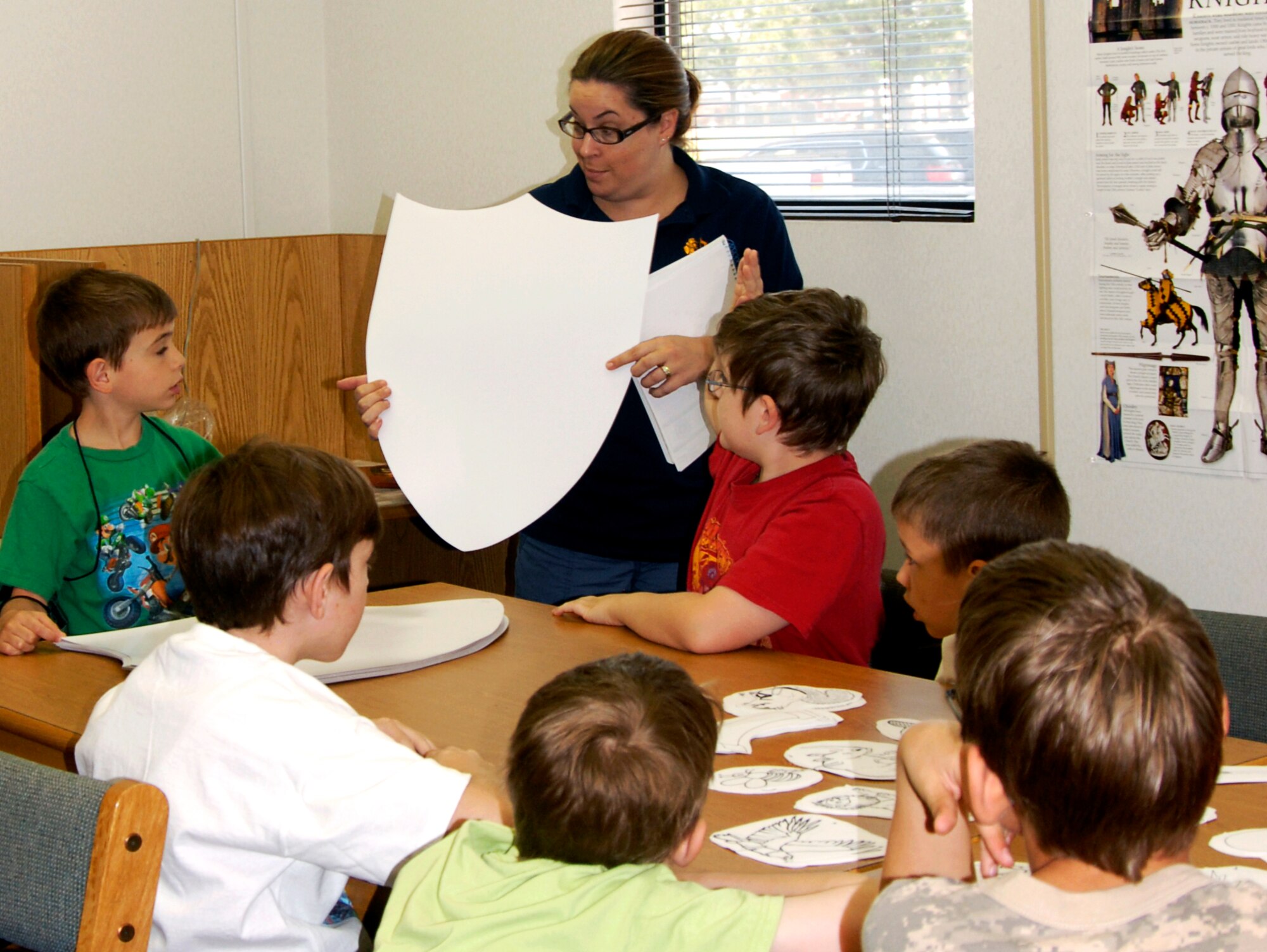 GOODFELLOW AIR FORCE BASE, Texas – Susan Dearing, Goodfellow library aid, talks to youths about decorating their own shield during the weekly summer reading program June 15 at the library here.  More than 100 youths are signed up for this year’s program, A Midsummer Knight’s Read, where youths learn about the Renaissance Era. (U.S. Air Force photo/Connie Hempel)