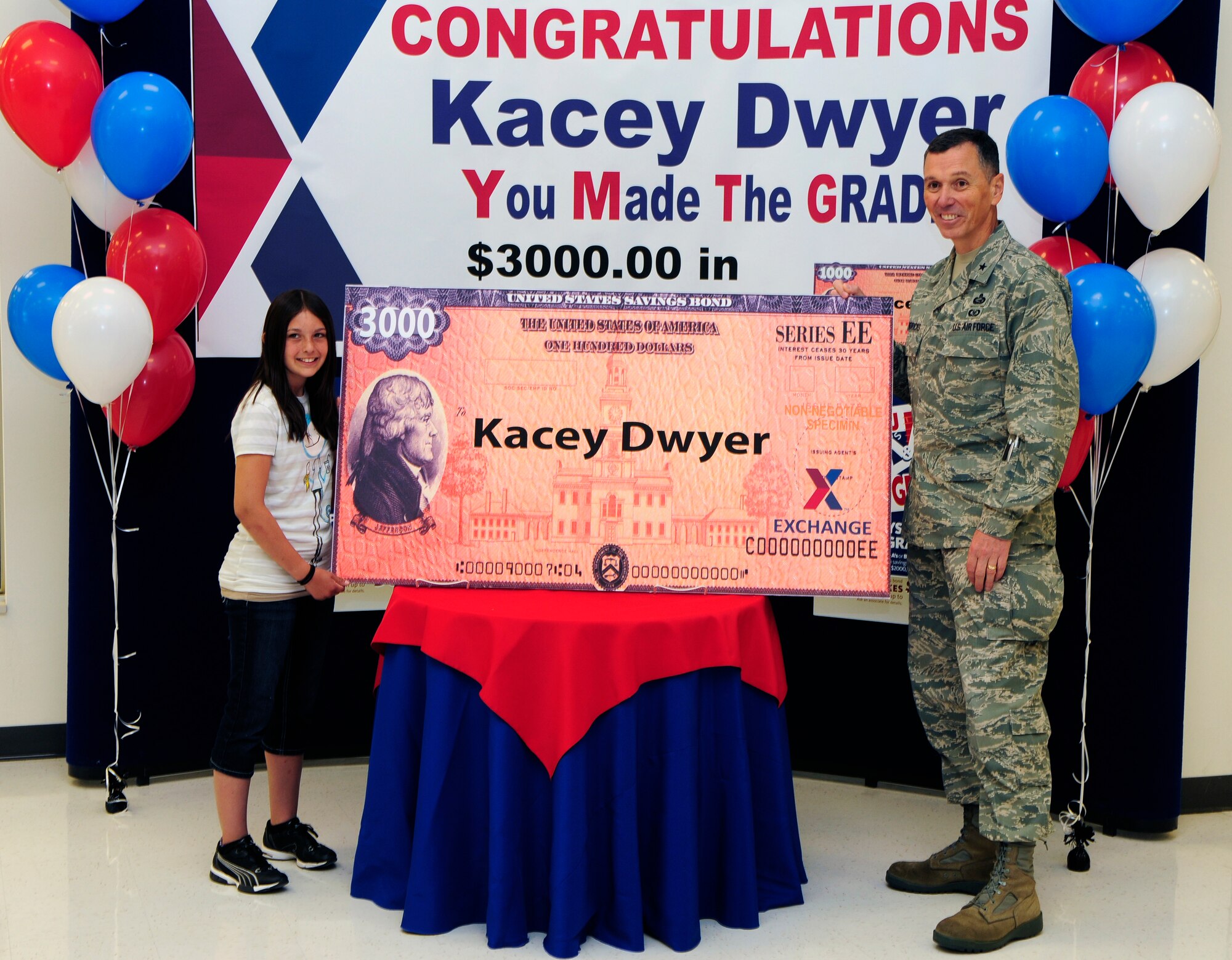 Kacey Dwyer accepts a savings bond from Army Air Force Exchange Service June 7, 2011, Eielson Air Force Base, Alaska.  Kacey registered for the drawing and was formally announced AAFES "You Made the Grade" second-place winner by Brig. Gen. Francis Hendricks, the AAFES deputy commander.  Kacey is the daughter of Master Sgt. Daniel Dwyer who is assigned to the 354th Force Support Squadron. (U.S. Air Force photo/Airman 1st Class Yash Rojas)