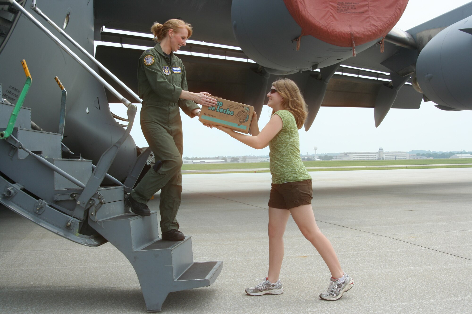 WRIGHT-PATTERSON AIR FORCE BASE, Ohio – Capt. Jackie Fleming, 89th Airlift Squadron, pilot, takes a box of Girl Scout cookies from Andi Repke, daughter of Lt. Col. Neil Repke, 445th Airlift Wing Command Post, chief, June 5.  More than a dozen boxes were donated by various Girl Scout Troops of St. Andrew School in Upper Arlington, Ohio, for the men and women serving in the AOR. (U.S. Air Force photo/Senior Airman Mikhail Berlin)