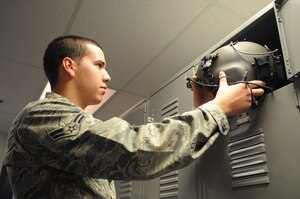 Airman 1st Class Richard Rodriguez, 811th Operation Support Squadron aircrew flight equipment technician, stows a flight helmet in a pilot's locker after he inspected it for function and servicability.  AFE inspects and maintains other equipment as well, to include night-vision goggles, life preservers and survival kits. (U.S. Air Force photo by Senior Airman Torey Griffith)(released)