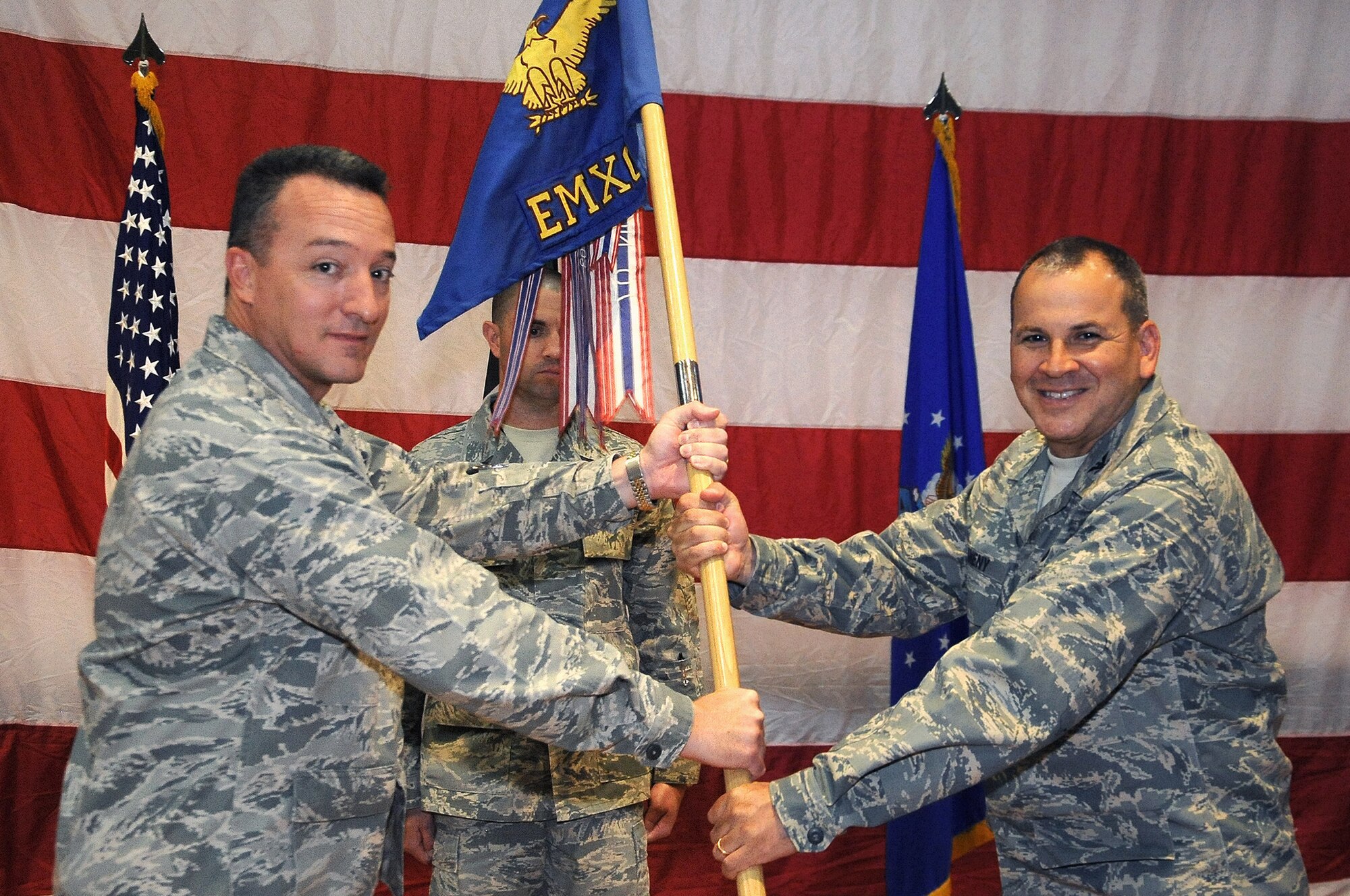 Col. Patrick Mordente, 386th Air Expeditionary Wing commander, left, passes the 386th Expeditionary Maintenance Group guide-on to Col. Paul J. McAneny June 14 during a change of command ceremony at an undisclosed location in Southwest Asia. Colonel McAneny assumed command of the 386th EMXG from Col. Ricky Thompson. (U.S. Air Force photo by Master Sgt. Carlotta Holley)