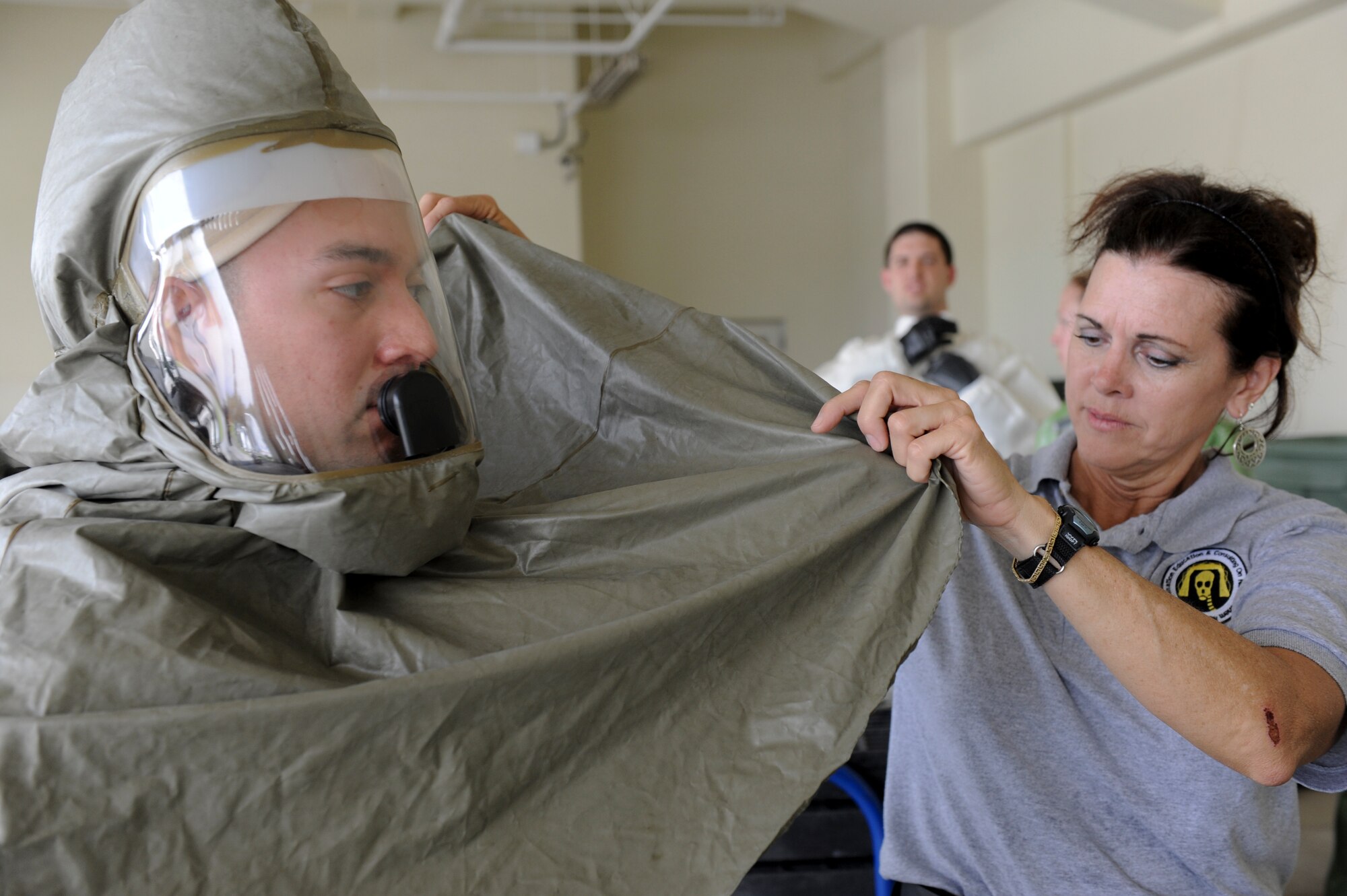 Theresa Casey, Decontamination Education and Consulting on Chemical Biological and Nuclear Decontamination instructor, checks a seal on an Airman’s KAPPLER protective suit at the 18th Wing Medical Group, June 9. The training ensures the in-place patient decontamination team knows how to rapidly and effectively deploy the equipment for timely response. (U.S. Air Force photo/ Airman 1st Class Brooke Beers) 