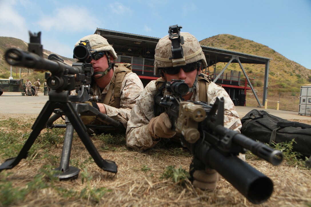 Lance Cpl. Benjamin V. Stout, a Barnesville, Minn., native and machine gunner with the 11th Marine Expeditionary Unit's maritime raid force (MRF), assists machine gunner Lance Cpl. Josh M. Tasior from Dallas, as they hold security on the outer cordon of a target site during an MRF training course here June 15. The security provided by the cordon allows other Marines to safely clear buildings of possible threats.::r::::n::