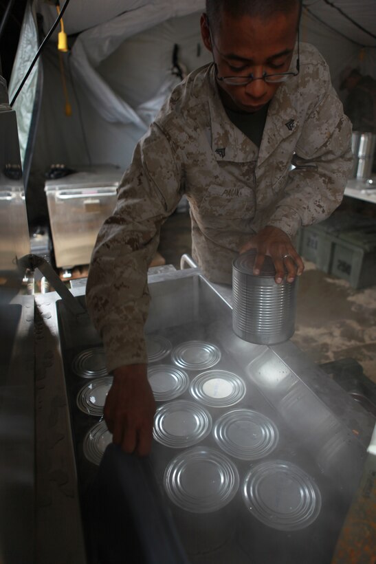 Cpl. Jose A. Pagan, a food service specialist with Battalion Landing Team 3/1, 11th Marine Expeditionary Unit, places cans of green beans into a heating system here June 15.  Pagan and his team prepared an evening meal for an estimated 600 Marines and sailors during the MEU's first field exercise since coming together in May. Pagan, 24, is a Youngstown, Ohio, native.