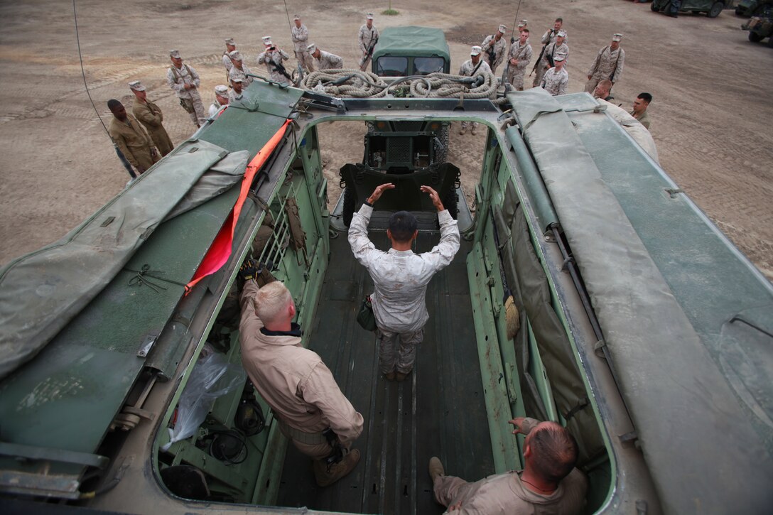 Marines with Battalion Landing Team 3/1 work together to fit a 120mm mortar into a tracked vehicle for the first time here June 15. The Marines are a part of a field exercise conducted by the 11th Marine Expeditionary Unit.