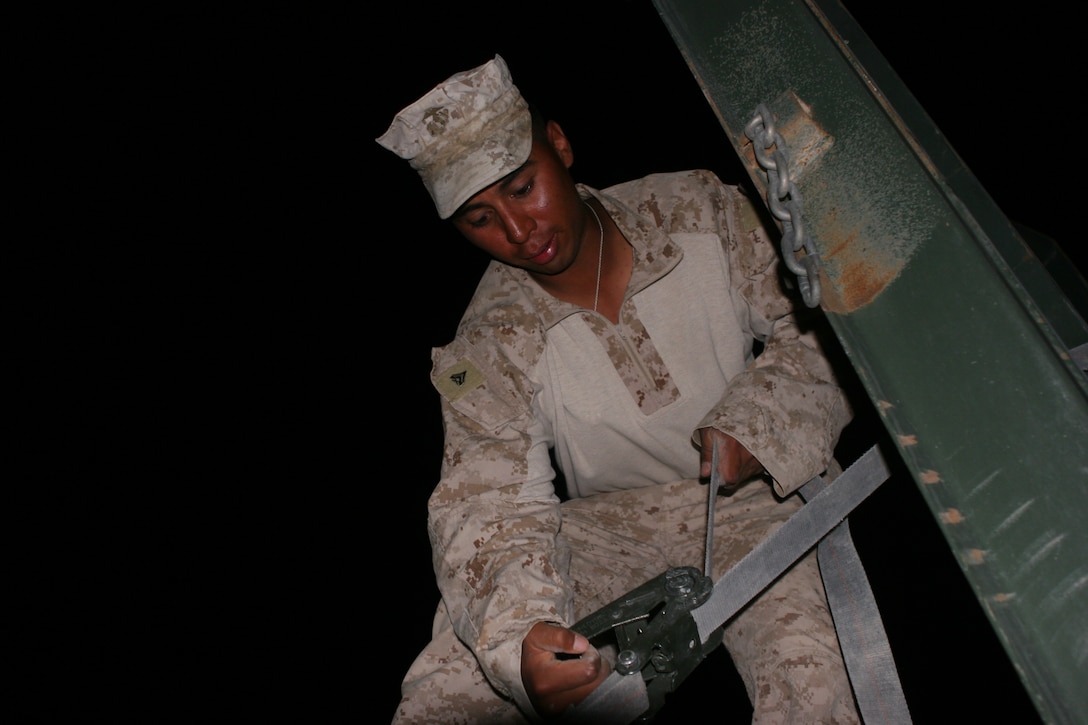 Cpl. Rene Sotelo, the loadmaster for 2nd Platoon, Truck Company B, Headquarters Battalion, 1st Marine Division, tightens down a ratchet strap after off loading heavy equipment during a resupply at Forward Operating Base Jackson in Sangin, June 15. Marines of Truck Company B, deployed out of Camp Margarita aboard Camp Pendleton, Calif., to serve as the combat logistic resupply element for 1st Battalion, 5th Marine Regiment. The platoon runs CLR trains six nights a week in addition to operational and security support missions in support of 1/5. Sotelo, 23, is from Chicago and graduated from Martin West High School in 2006.