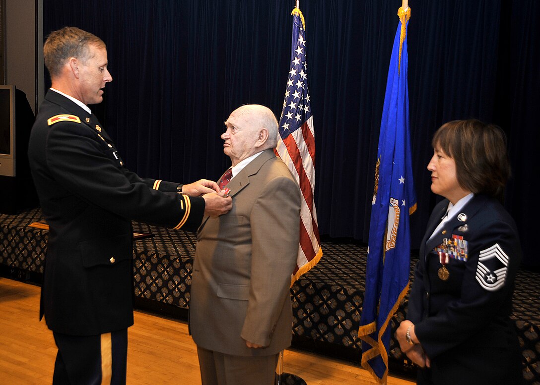 Army Col. Timothy Coffin, the deputy commander of Space and Missile Defense Command and Army Strategic Command, pins the Bronze Star Medal on retired Army Sgt. 1st Class Daniel Porter, as his daughter, Chief Master Sgt. Nancy Geisler, looks on during her retirement ceremony June 13, 2011, at Peterson Air Force Base, Colo. Sergeant Porter earned the Bronze Star Medal for his service in Vietnam from 1969 to 1970, while serving with the 4th Infantry Division, currently located at Fort Carson, Colo. (U.S. Air Force photo/Dennis Howk)
