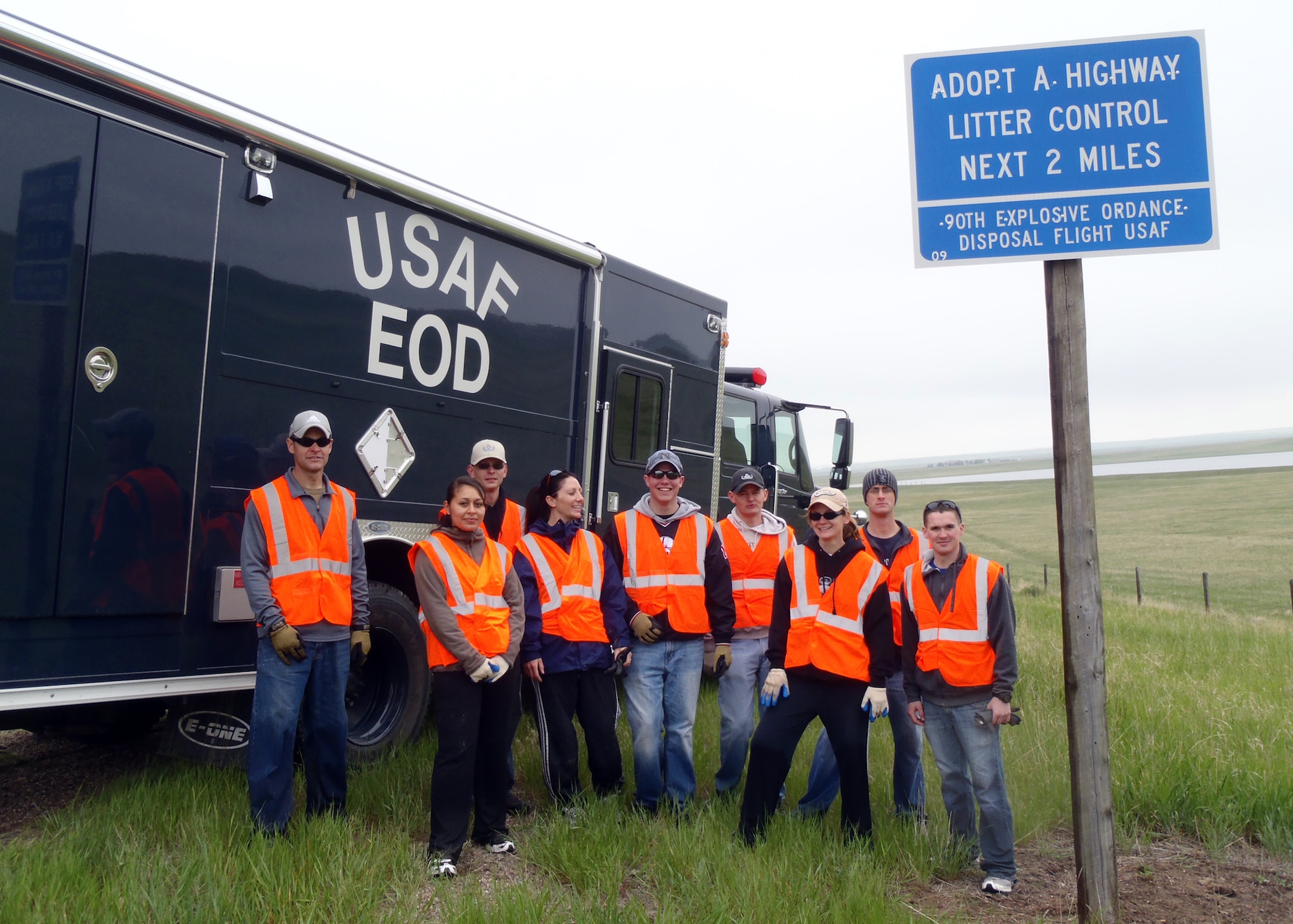 Master Sgt. Joshua King, Senior Airman Andrea Rasmussen, Tech. Sgt. David Csizmar, Mesa Anderson, Airman 1st Class Brandon Miller, Senior Airman Sherman Miller, Tech. Sgt. Bridget Crudden, Staff Sgt. Andrew Krueger and Airman 1st Class Adam Hickman, from 90th Explosive Ordinance Disposal Flight pose next to their Adopt A Highway sign after cleaning their two mile stretch of road. (Courtesy photo)