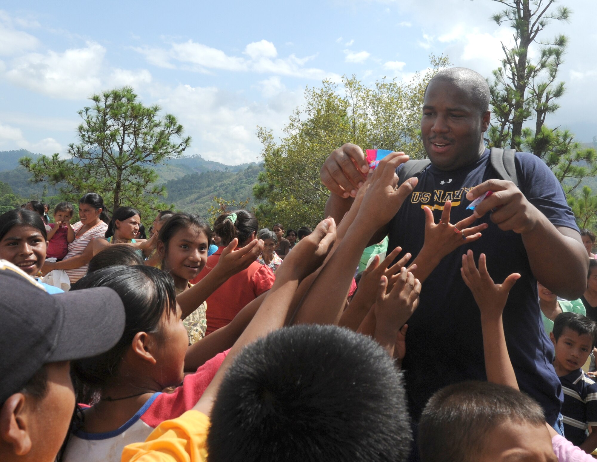 Petty Officer 2nd Class Corey Johnson hands out candy to children June 11, 2011, at an isolated village near Comayagua, Honduras. More than 120 Joint Task Force-Bravo members from Soto Cano Air Base, Honduras, hiked two miles up steep terrain to deliver food to people living in the town. (U.S. Air Force photo/Tech. Sgt. Matthew McGovern)