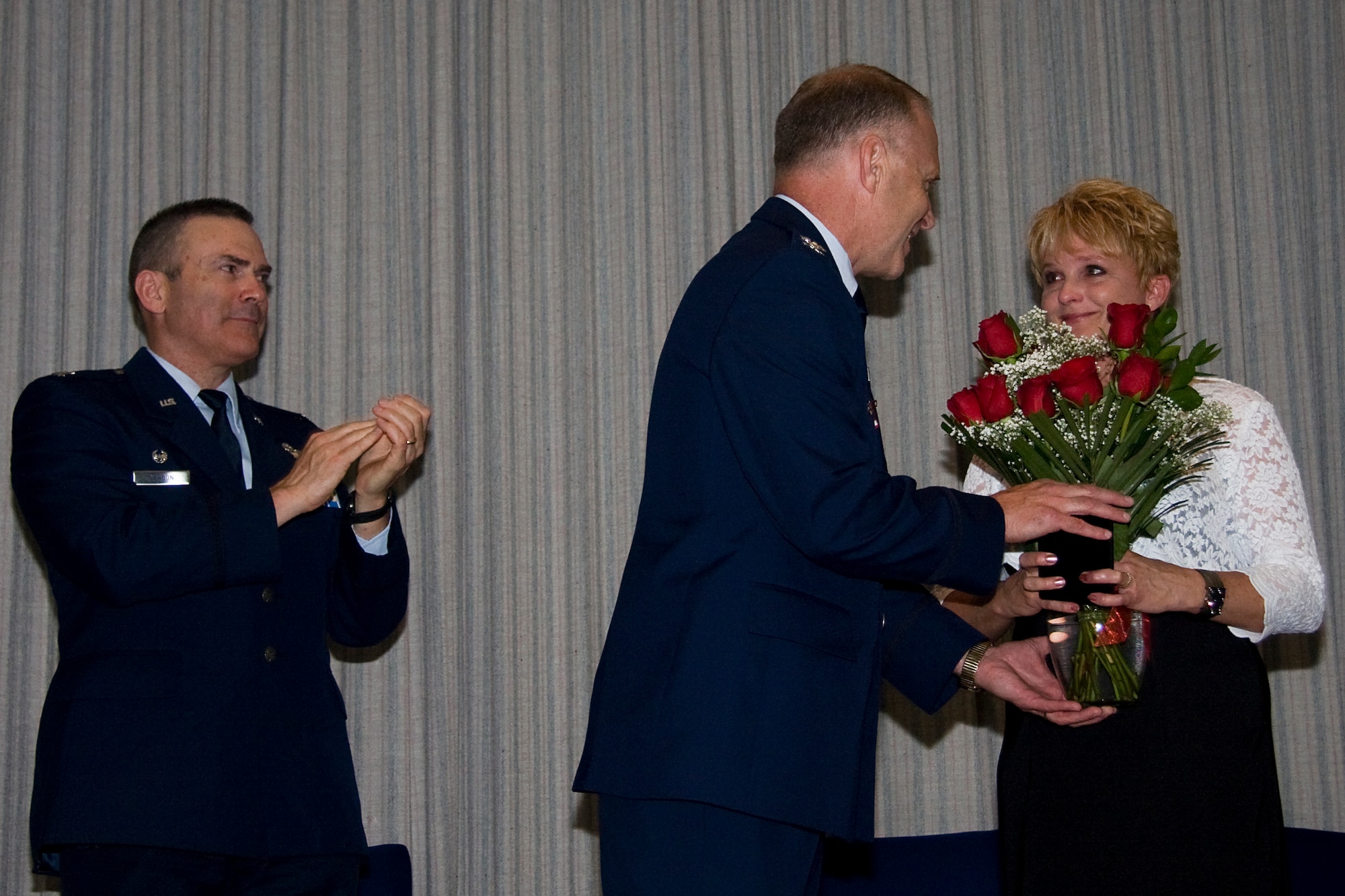 GRISSOM AIR RESERVE BASE, Ind. -- Col. Tim Cox, center, presents his wife, Tanya, with a bouquet of roses during his retirement ceremony here May 14, thanking her for her support of his 30-year Air Force career as Col. William T. "Tim" Cahoon applauds them both. Colonel Cox retired at the end of May as the 434th Air Refueling Wing vice commander. Colonel Cahoon is the 434th ARW commander. (U.S. Air Force photo/Tech. Sgt. Mark R. W. Orders-Woempner) 
