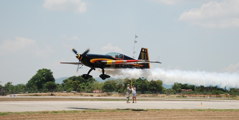 Aerial stunt performer Patty Wagstaff performs a high-speed low pass underneath a ribbon being held by a U.S. Air Force member and civilian at an air show June 11, 2011, at Colonel Armando Escalon Espinal Air Base, Honduras. This annual event drew more than 10,000 spectators, raised money for a local civilian hospital and bolstered friendships between the military and civilian aviation communities of the U.S. and Honduras. (U.S. Air Force photo/Capt. David McCain)