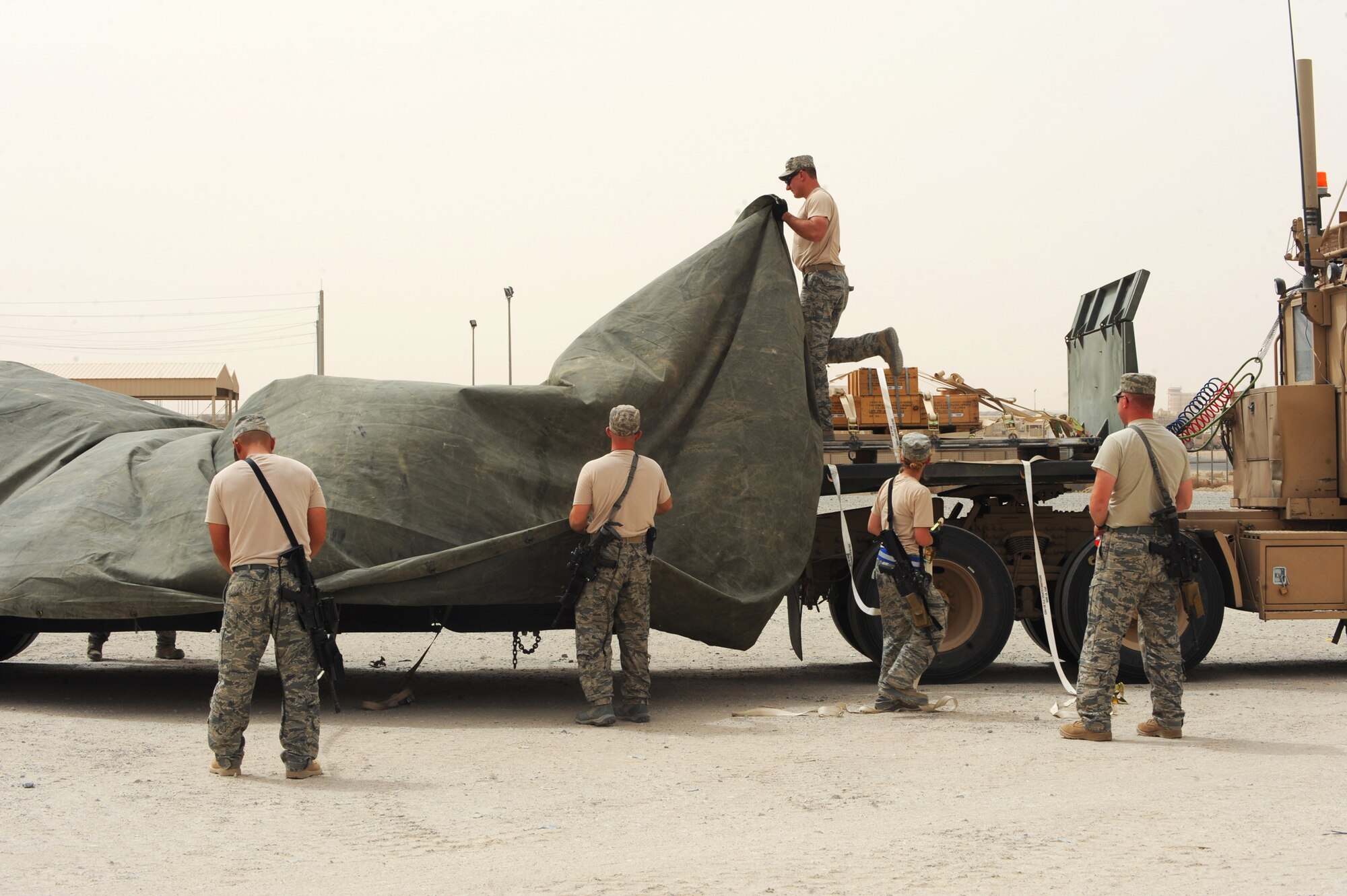 Combat truckers assigned to the 387th Expeditionary Logistics Readiness Squadron help each other unstrap their cargo while waiting for for forklifts to arrive during a local convoy mission. Due to mission priorities and procedures, these Airmen can sometimes wait long hours before returning, eating and sleeping. In a recent mission, they waited 13 hours after having driven six hours to their destination. (U.S. Air Force photo by Senior Airman Cynthia Spalding)