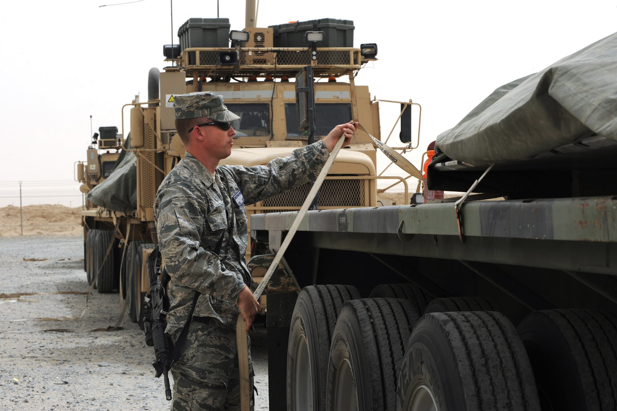 Lt. Col. Christopher Boone, 387th Expeditionary Logistics Readiness Squadron commander, helps unstrap cargo after arriving at the drop-off location during a local convoy mission. According to Colonel Boone, he  rode along with his Airmen to not only gain an appreciation for what his Airmen endure, but to experience some of the same delays they regularly endure. (U.S. Air Force photo by Senior Airman Cynthia Spalding)

