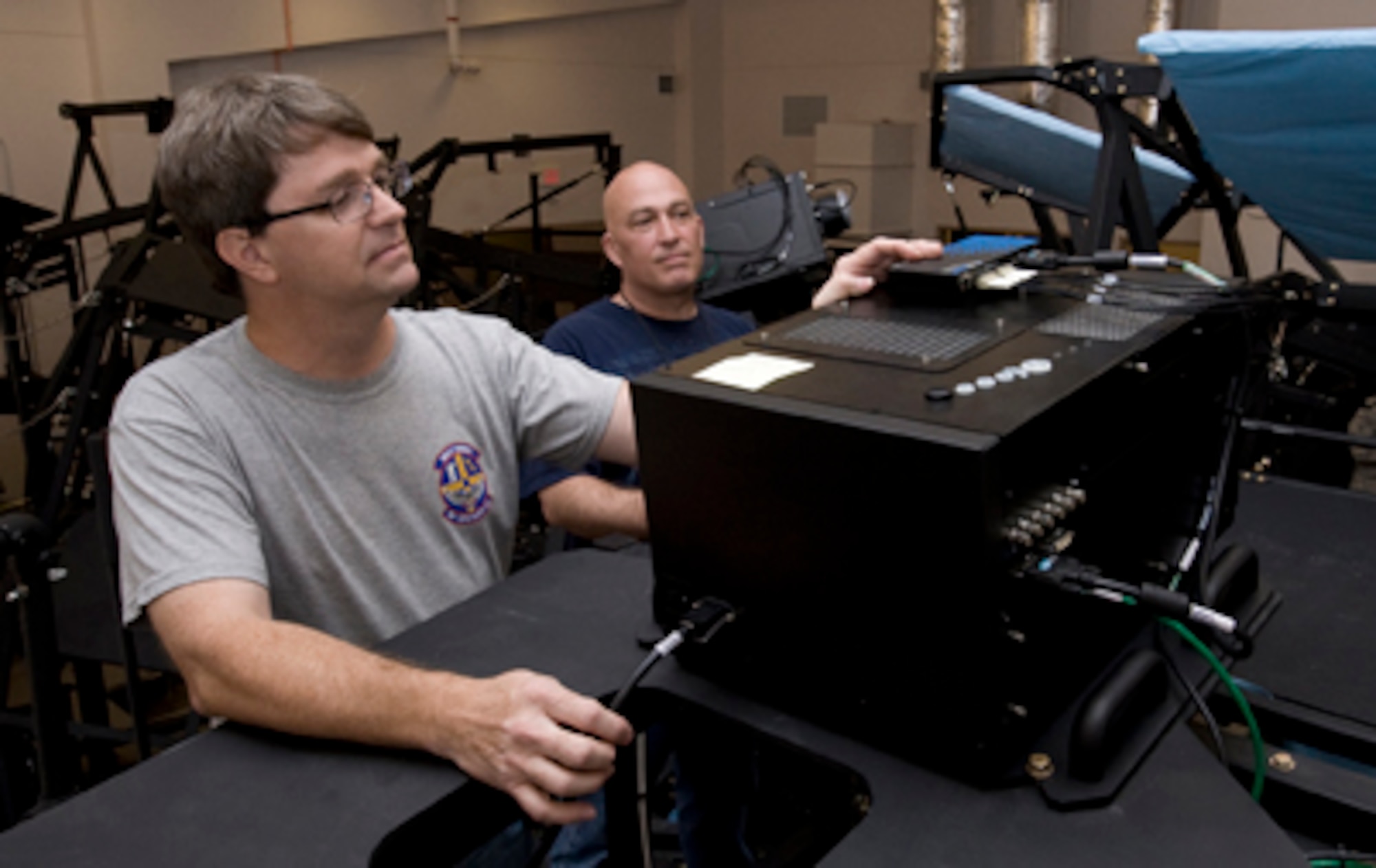 Brian Miller, an L3 Communications assistant site supervisor, and Brian Smith, the lead technician, review the functions of a projector from the F-16 Fighting Falcon Mission Training Center flight simulator June 13, 2011, during the installation phase at Nellis Air Force Base, Nev. The simulator will allow F-16 pilots to practice aerial maneuvers, formations, and air-to-air combat with a 360-degree view. This simulator is one of four to be constructed at Nellis AFB. (U.S Air Force photo/Senior Airman Stephanie Rubi)