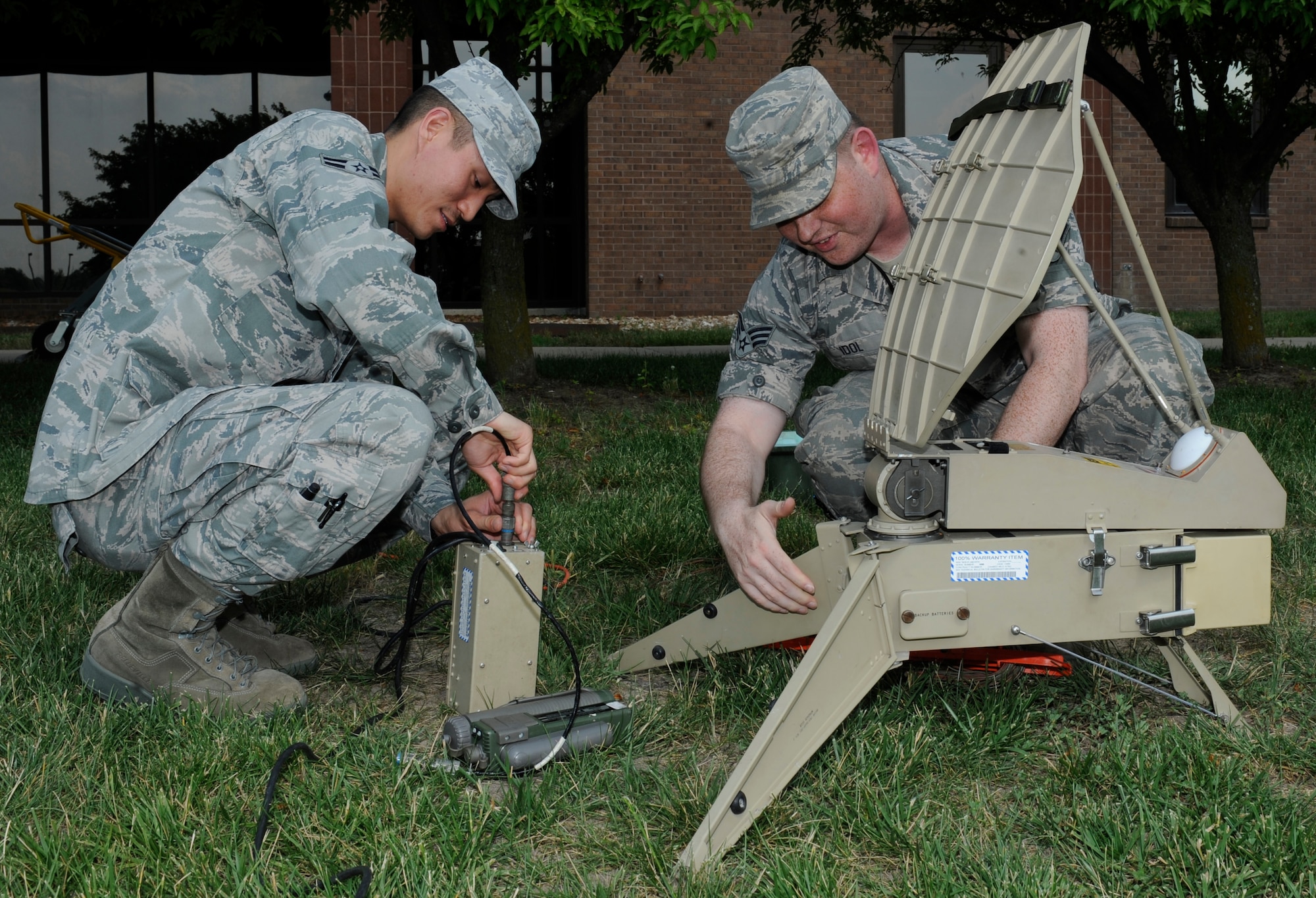 WHITEMAN AIR FORCE BASE, Mo. -- Airman 1st Class Joseph Lee and Senior Airman Allen Idol, 509th Communications Squadron radio frequency transmission systems technicians, connect the external power supply unit to a Single Channel Anti-Jam Portable (SCAMP) terminal for its monthly verification June 10. (U.S. Air Force photo by Senior Airman Alexandra M. Boutte) 
