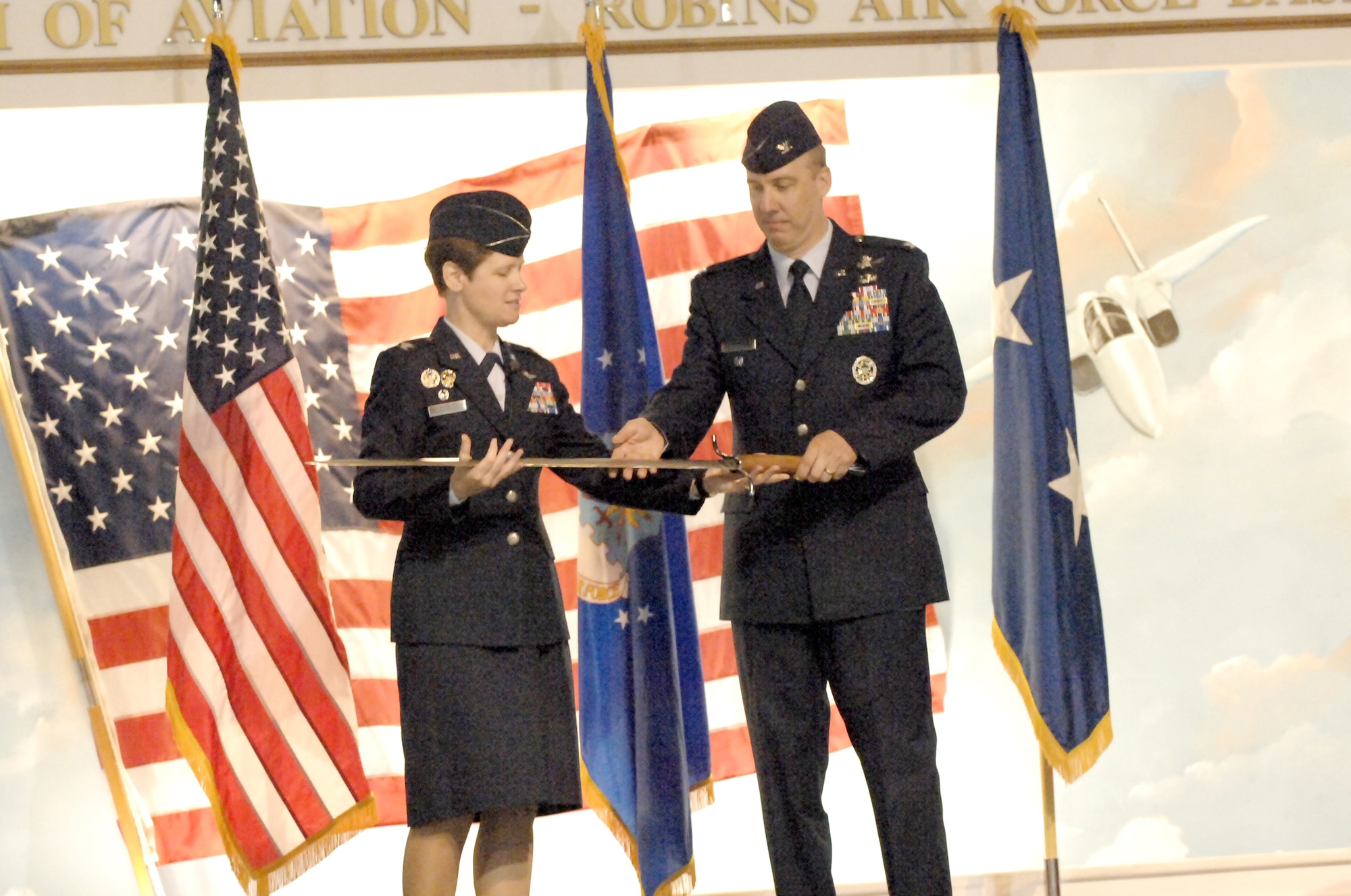 Col. Theresa Giorlando, presents Col. Joseph Scherrer, new 689th Combat Communications Wing commander, with a sword after relinquishing command of the wing. U. S. Air Force photo by Ray Crayton