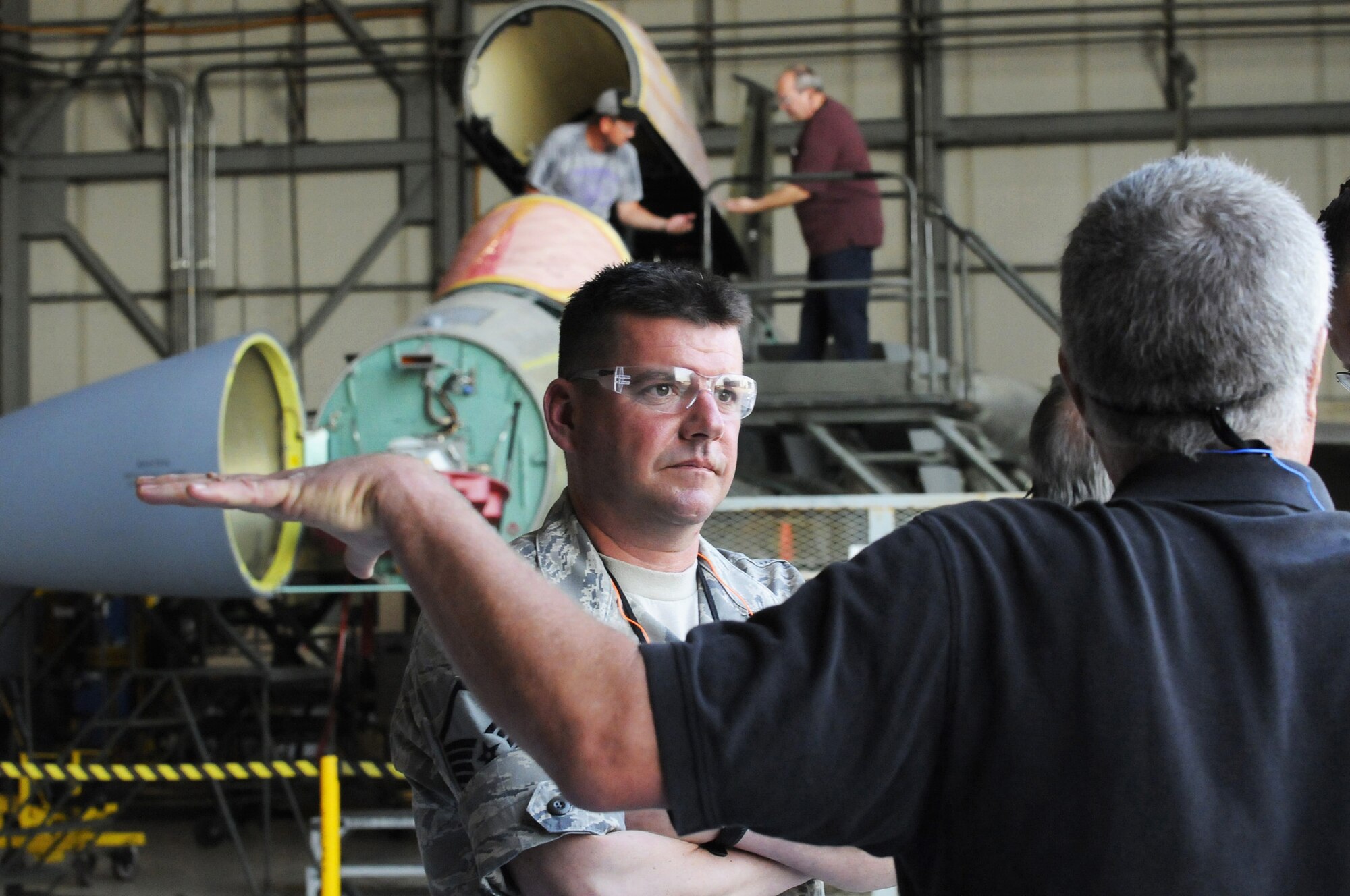 Master Sgt. Thomas Ball, 142nd Fighter Wing, talks with Mark Krautkremer, F-15 customer relations and quality assurance, while at Robins. Ball, an F-15 crew chief, was here observing programmed depot maintenance on the F-15C being worked on in the background.U. S. Air Force photo by Sue Sapp