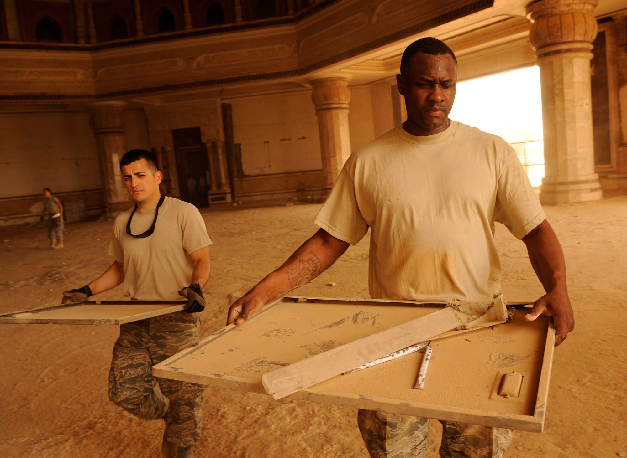 BAGHDAD, Iraq -- Staff Sgt. Justin Loterg and Tech. Sgt. Brian Jones haul out old office equipment and life support equipment inside Victory Over America Palace June 11. The two Airmen were among more than 35 others who volunteered to clean up the palace before Iraqi officials reclaim the facility. Sergeant Loterg is an Air National Guardsmen deployed from Birmingham, Ala. Sergeant Jones is deployed from Royal Air Force Lakenheath, England, and calls his home Rochester, N.Y. (U.S. Air Force/Tech. Sgt. Jason Lake)
