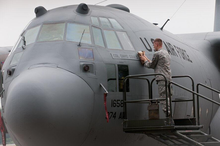 YOKOTA AIR BASE, Japan -- Staff Sgt. Jonathan Callahan, flying crew chief of the 374th Aircraft Maintenance Squadron, reveals the name of the new 374th Operations Group commander, Col. David Gould II, on the 374th OG flagship during an assumption of command ceremony June 16, 2011, at Yokota Air Base, Japan. (U.S. Air Force photo/Osakabe Yasuo) 