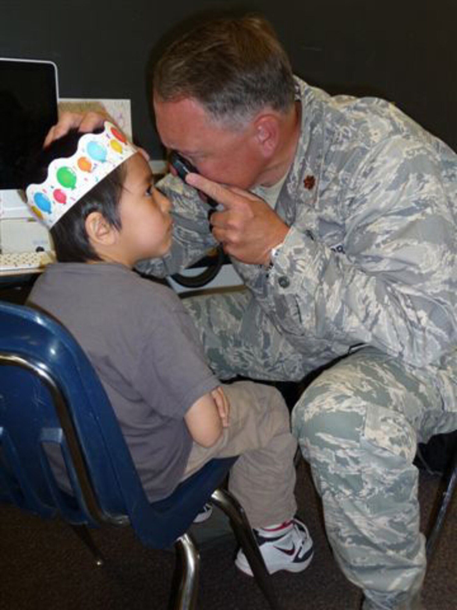 Maj. David Parker, 403rd Aeromedical Staging Squadron officer in charge of optometry, performs a routine eye exam for a young patient in the village of Ruby, Alaska, during Operation Arctic Care. For this annual two-week mission, various military and government medical professionals travel to remote villages to treat native Alaskans with limited access to general health care. (Courtesy photo)