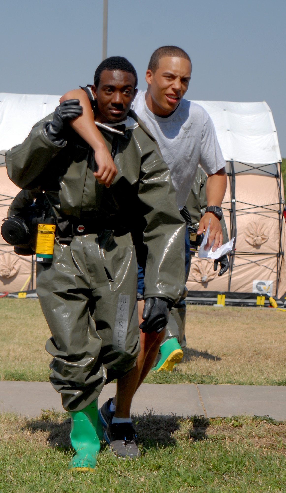 GOODFELLOW AIR FORCE BASE, TEXAS--Airman 1st Class Keiyon Monroe, 17th Medical Group dental technician, helps Airman Basic Cameron Greene, 316th Training Squadron student, inside the clinic for follow on decontamination during the exercise June 16. The scenario for the exercise was an unknown assailant tossed gas canisters into the theater contaminating those inside. (U.S. Air Force photo/Airman 1st Class Michael Smith)
