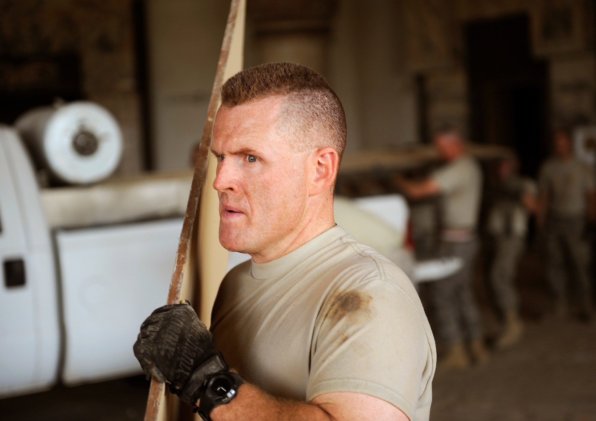 Senior Master Sgt. Jeff Gideon, from the 447th Air Expeditionary Group, hauls out plywood from inside the Victory Over America Palace as more than 35 volunteers cleaned up the palace June 11, 2011, at Camp Slayer outside Baghdad, Iraq.  (U.S. Air Force photo/Tech. Sgt. Jason Lake)