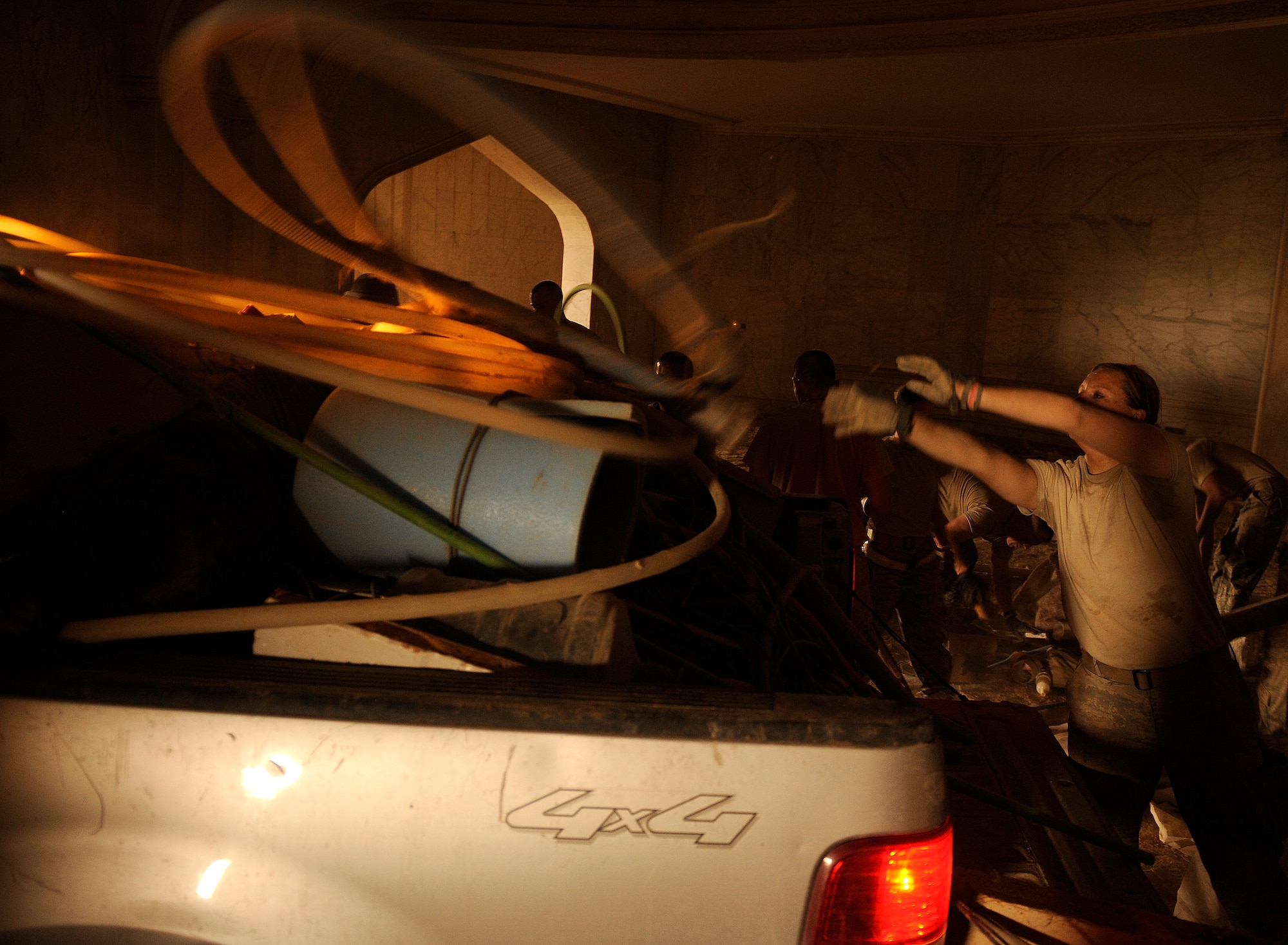 Staff Sgt. Teresa Pavljuk, a 447th Expeditionary Logistics Readiness Squadron aerial porter, tosses debris and old office equipment into a pickup truck as more than 35 volunteers cleaned up the inside of the Victory Over America Palace June 11, 2011, at Camp Slayer outside Baghdad, Iraq.  (U.S. Air Force photo/Tech. Sgt. Jason Lake)
