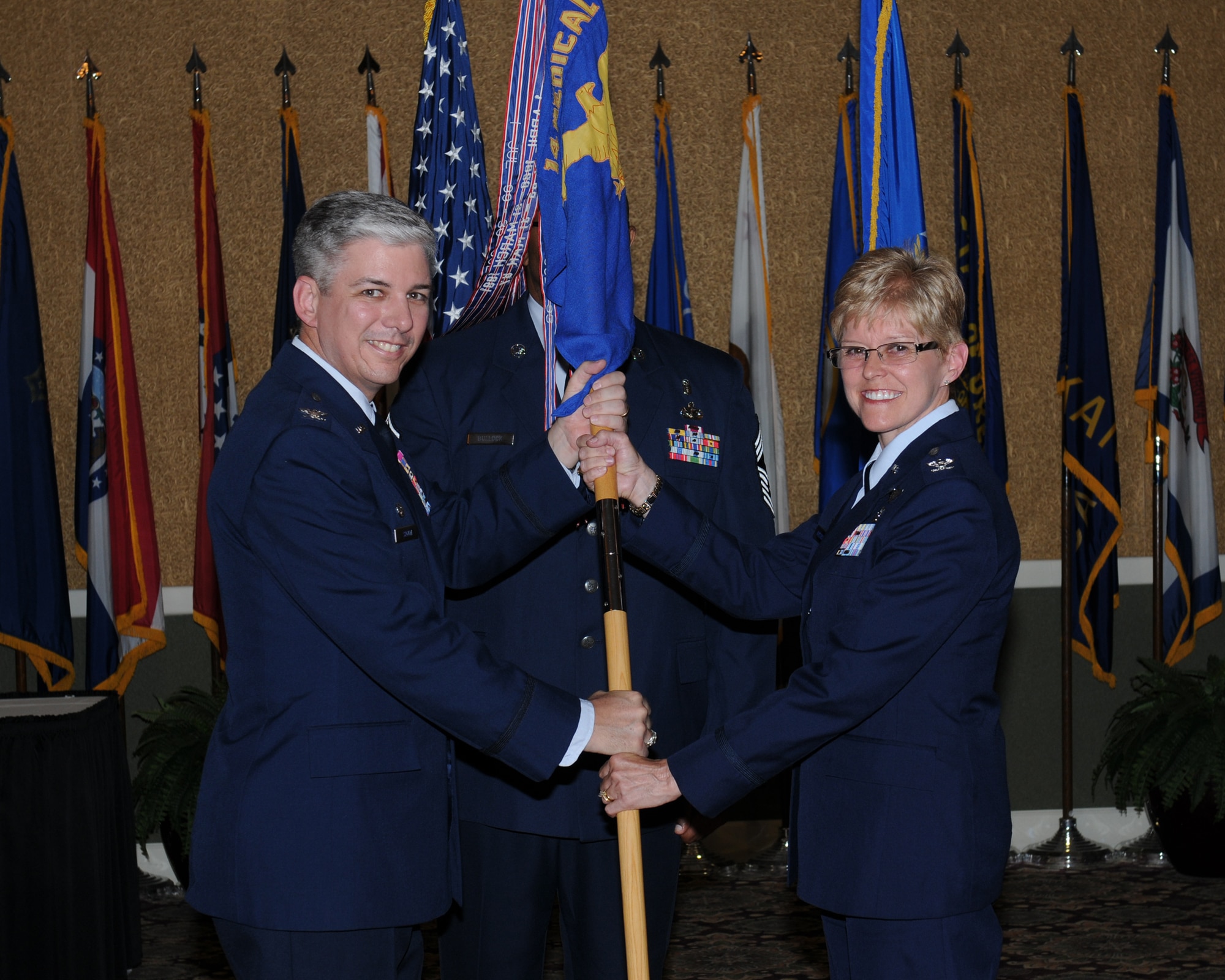 Col. Barre Seguin, 14th Flying Training Wing Commander passes the 14th Medical Group guidon to Col. Billye Hutchison, 14th MDG Commander during a change of command ceremony on June 14. Colonel Hutchison was previously the Chief, Medical Force Development and Formal Training Division, Air Education and Training Command, Randolph AFB, Texas. (U.S. Air Force photo/Melissa Doublin)
