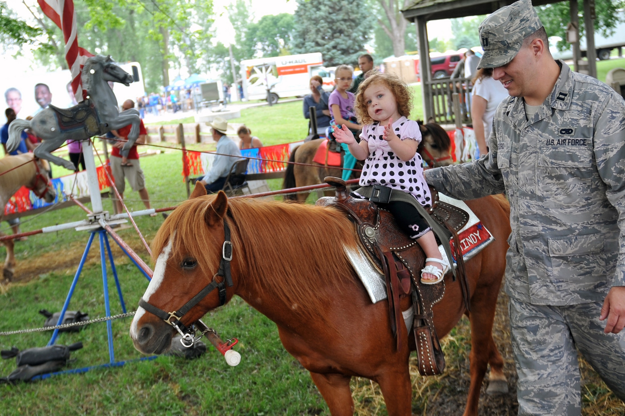 Air Force Capt. Brian Florio, 55th Maintenance Squadron, guides his daughter Sophia around for a pony ride at the Offutt Advisory Council's Annual Offutt Appreciation Picnic June 10, 2011 at the Offutt Air Force Base, Neb., Base Lake. Team Offutt employees and their families enjoyed a day in the sun that included free food, beverages and entertainment during the event. (U.S. Air Force photo by Jeff W. Gates/Released)