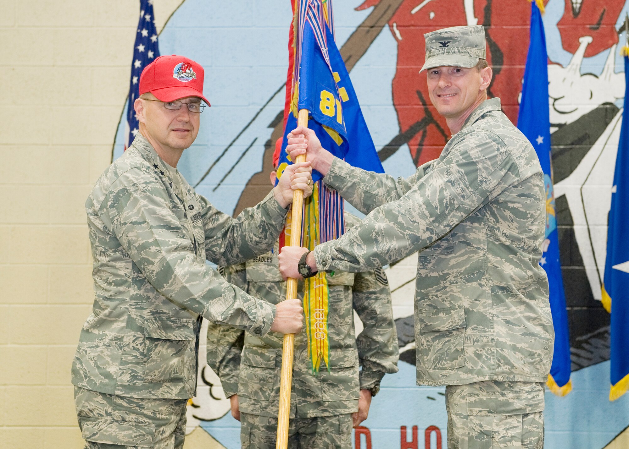 Col. Mark Zimmerhanzel accepts command of the 819th Red Horse Squadron from Maj. Gen. Stephen Hoog, 9th Air Force commander, June 14 at the Airfields Hangar. Senior Master Sgt. Ronald Beadles, 819th Red Horse Squadron first sergeant, looks on. (U.S. Air Force photo/Beau Wade)