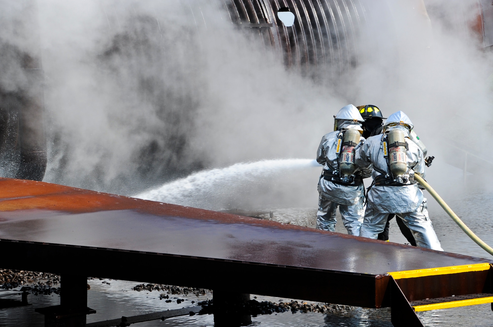 Airmen and Marines from Joint Base McGuire-Dix-Lakehurst successfully extinguished fires consuming a mock training aircraft here June 10. This marks the first time the Airmen and Marines conducted joint fire-fighting training here. The mock aircraft trainer is doused with the remaining water inside the JB MDL FD trucks when the training is complete. (U.S. Air Force photo by Airman 1st Class Dennis Sloan/Released)