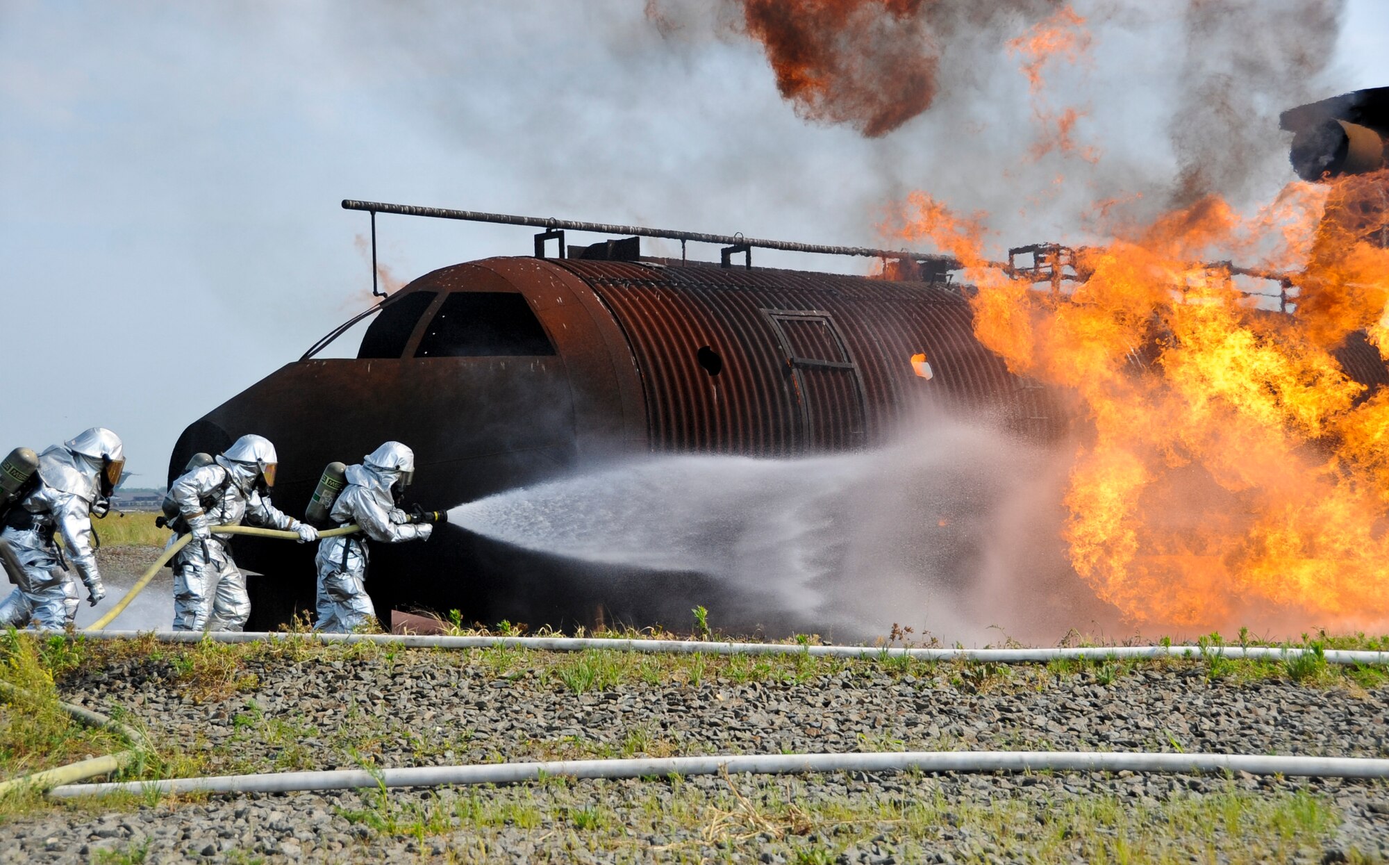 Airmen and Marines battle through the fire’s extreme heat as they fight the rising flames that surround the mock aircraft frame. Both units worked together to extinguish four fires in and around the training aircraft. Qualified trainers control the location and intensity of the fires on the mock aircraft trainer from a control both nearby. The fires are fed and controlled via underground gas lines. (U.S. Air Force photo by Airman 1st Class Dennis Sloan/Released)