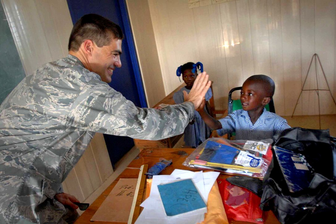U.S. Air Force Maj. Joe Martinez gives a high five to a student during a school visit in the Artibonite department of Haiti, June 16, 2011. Martinez is assigned to U.S. Southern Command.
