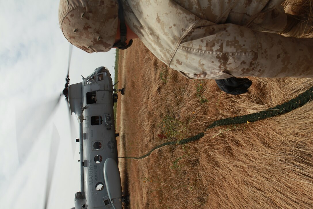 Lance Cpl. Justin Wiley, a Coleman, Texas native and forward observer with the 11th Marine Expeditionary Unit's maritime raid force, straightens a rope attached to a CH-46E Sea Knight in preparation for Marines with the unit to fast rope during an MRF training course June 17. Fast roping is a technique used to quickly descend into a target site without landing the aircraft.::r::::n::::r::::n::::r::::n::