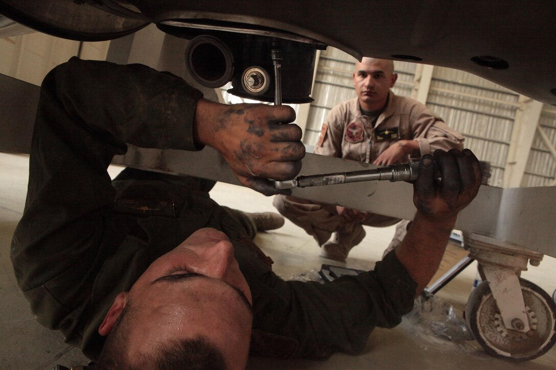 Cpl. Jason Cobain, a Marine Attack Squadron 513 powerline mechanic and West Hills, Calif., native, installs a valve on one of the squadron’s AV-8B Harriers while Sgt. Christopher Escobar, a VMA-513 powerline quality assurance representative and El Paso, Texas, native, supervises in the squadron hangar at Kandahar Airfield, Afghanistan, June 18.