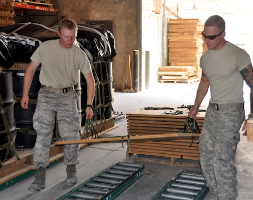 Cadet 1st Class Jordan Wittman, United States Air Force Academy Cadet Squadron 30, helps Staff Sgt. Matthew Jones lay out bare pallets on the assembly line at the U.S. Army Riggers detachment. Cadet Wittman is here on Deployed Ops, a summer program which sends Academy cadets to deployed locations. (U.S. Air Force photo/Cadet 1st Class Shaina Thompson)