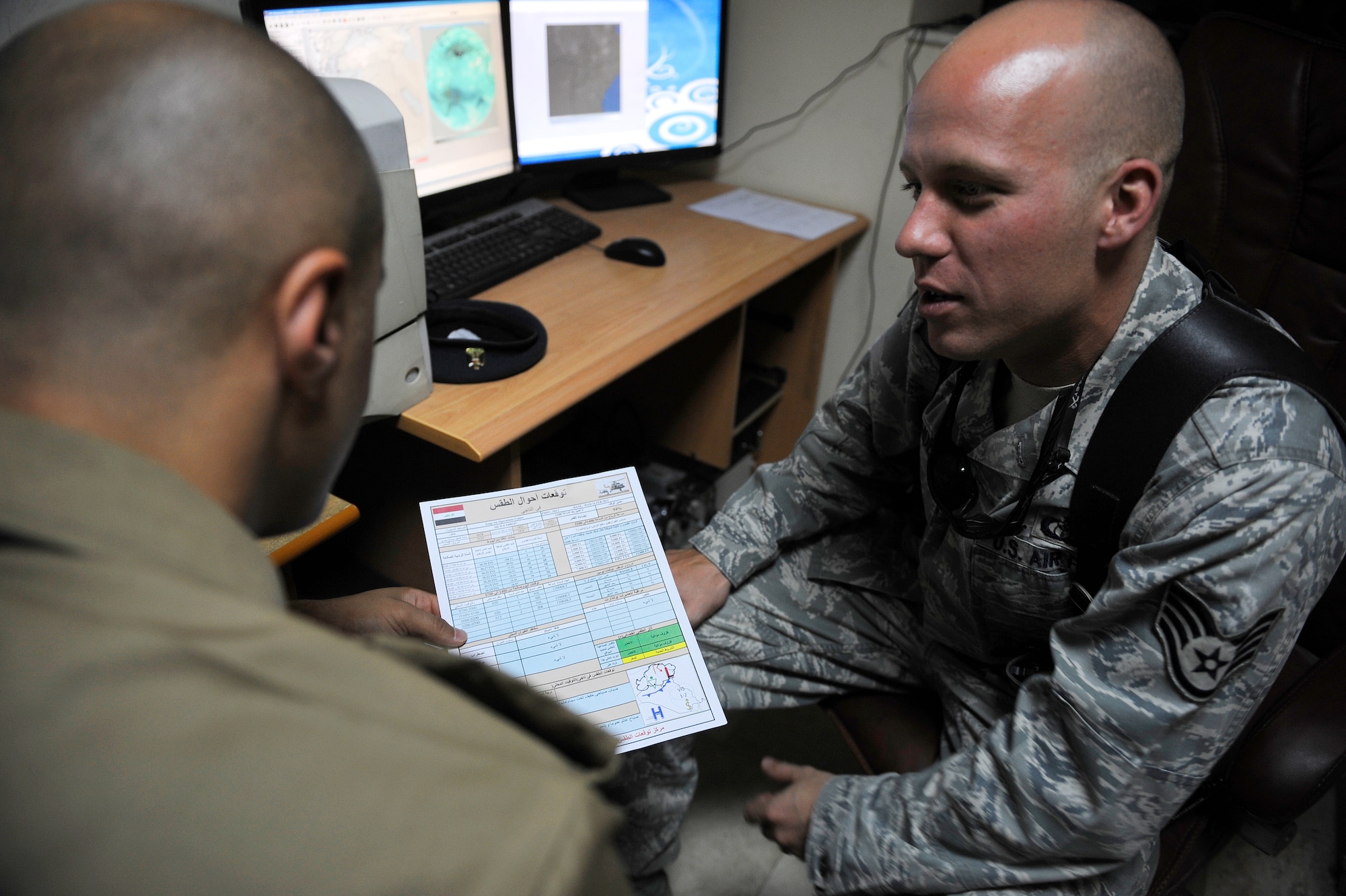 (Right) Staff Sgt. Dan Alexander, a weather advisor deployed from the Air Force Weather Initial Skills Course at Keesler Air Force Base, Miss., reviews weather data with an Iraqi air force weather forecaster at the IqAF's weather center June 14. U.S. Air Force weather advisors have been training the initial cadre of Iraqi air force weather forecasters over the past three years. The training entered a new chapter of autonomy last month when IqAF’s cadre began teaching 18 new cadets at the weather center in Baghdad. 
