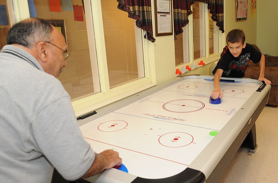 Zach Reed, 14, plays air hockey with Victor Santana, 2nd Force Support Squadron chief of youth programs, at the Youth Center on Barkdale Air Force Base, La., June 20. The Youth Center has a variety of recreational programs and day camps for children ages 5 through 18.(U.S. Air Force photo/Senior Airman Kristin High)(RELEASED) 