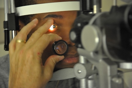 Brandon Mason (left), A Randolph AFB dependent, has his eyes examined by Lt. Col. Patrick Clark, Optometry Department chief of the Optical Radiation branch 711th Human Performance Wing Joint Base San Antonio, at RandolphAFB June 16. Col. Clark volunteers to see patients at Randolph to keep his certifications current.  (U.S. Air Force photo/Airman Alexis Siekert) (released)