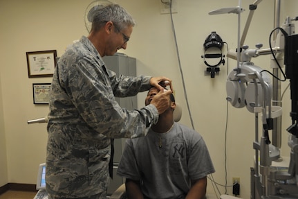Brandon Mason (left), A Randolph AFB dependent, has his eyes examined by Lt. Col. Patrick Clark, Optometry Department chief of the Optical Radiation branch 711th Human Performance Wing Joint Base San Antonio, at RandolphAFB June 16. Col. Clark volunteers to see patients at Randolph to keep his certifications current.  (U.S. Air Force photo/Airman Alexis Siekert) (released)