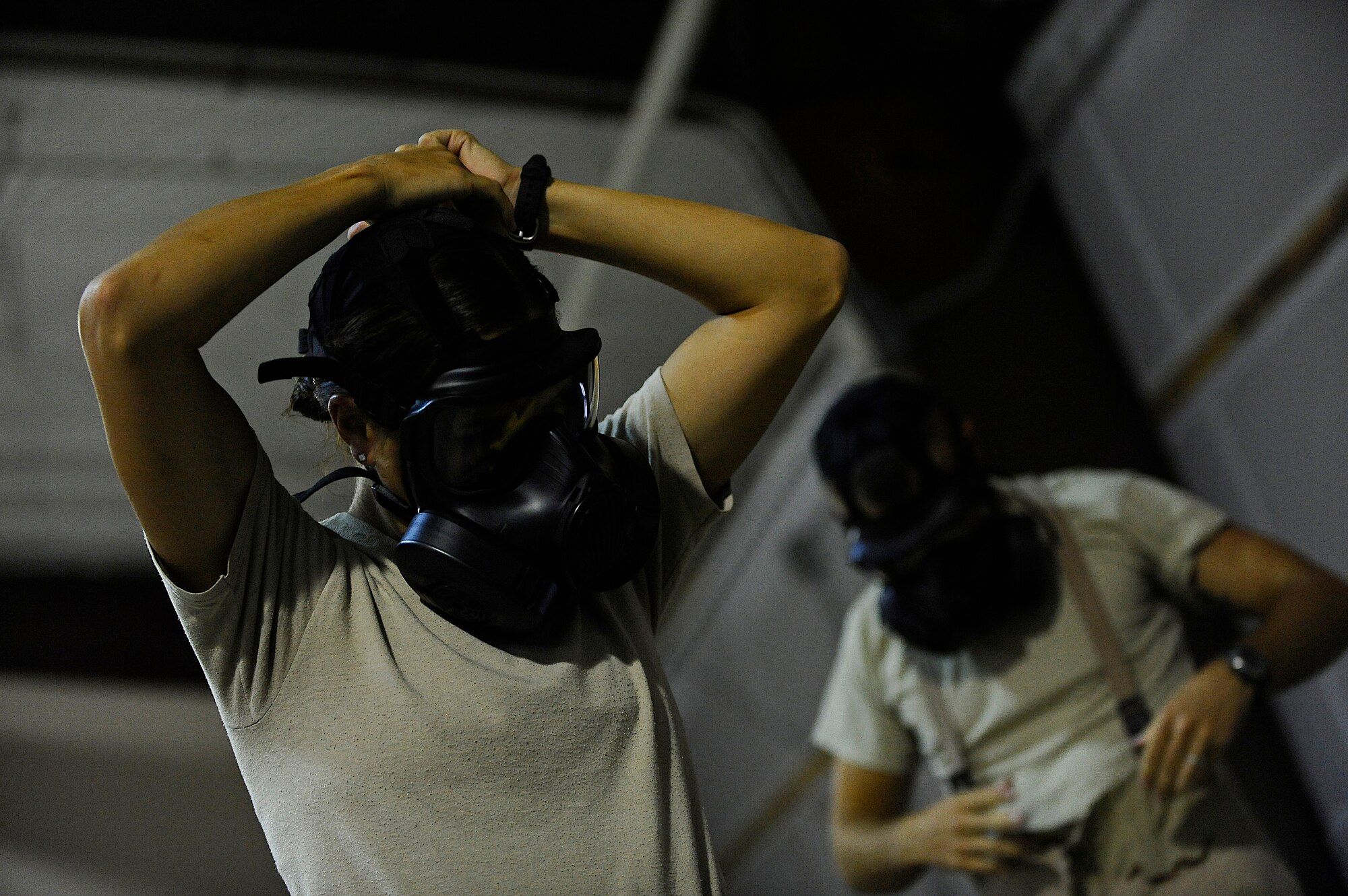 U.S. Air Force Staff Sgt. Morgan Colleran (left), 1st Special Operations Aerospace Medicine Squadron, dons her gas mask during a chemical, biological, radiological and nuclear training scenario, Hurlburt Field, Fla., June 14, 2011. Air Force Special Operations Command Airmen are preparing for the Air Force-level CBRN challenge. (U.S. Air Force photo by Staff Sgt. Julianne M. Showalter/Released)
